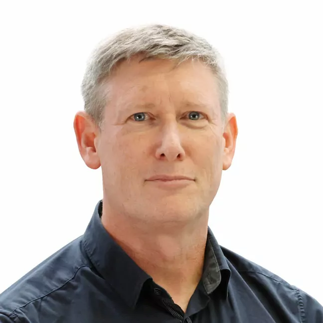 Head shot of a man with short silver hair, and dark blue shirt looking straight at the camera